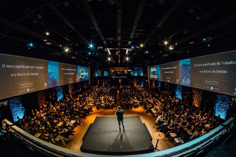 A speaker presenting on stage to a full audience at a product launch
