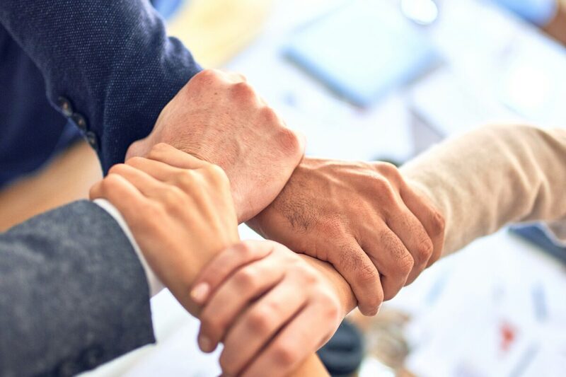 Team members joining hands to mark the end of a successful campaign